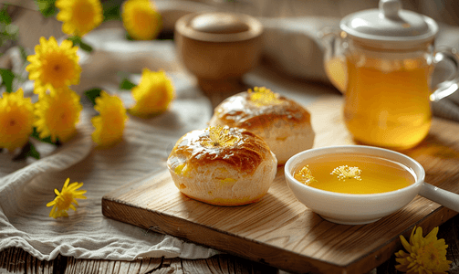 烤包子摄影照片_木制背景中的奶油面包和菊花茶