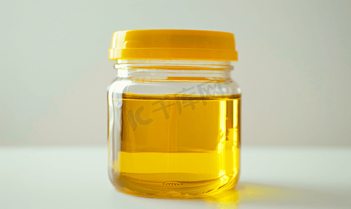 金色植物叶子摄影照片_塑料罐中的芥末油特写