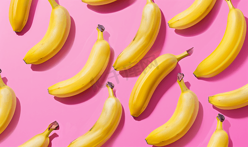 抽象水果摄影照片_粉红色背景上鲜黄香蕉的彩色水果图案从顶部看