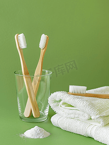 牙刷背景摄影照片_绿色背景中玻璃小苏打和毛巾中的木竹牙刷