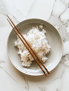 米饭筷子摄影照片_用筷子在白色盘子上煮米饭