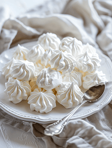 漂亮的白色蛋白饼配上银勺放在白色的盘子上白色的蛋糕