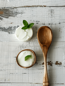 豆腐摄影照片_白木背景木勺上带薄荷叶的白酸奶
