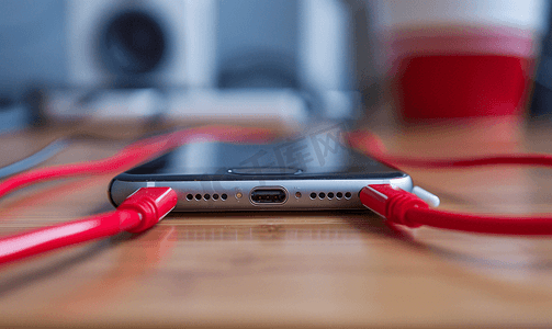 现代智能手机插入桌上的电源和音频电缆