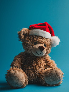 帽子冬天摄影照片_蓝色背景中戴着圣诞老人帽子的毛绒泰迪熊