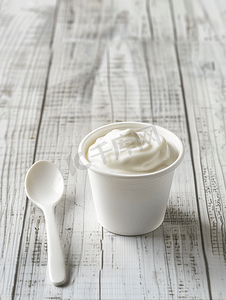 玻璃窗厚度摄影照片_白色木质背景上的酸奶杯和勺子