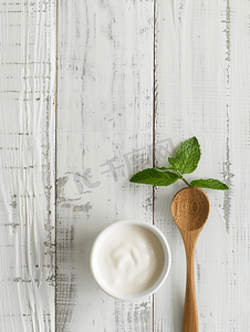 白酸奶白木背景上的木勺上有薄荷叶顶视图