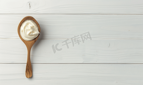 白色木质背景上木勺上的白色酸奶