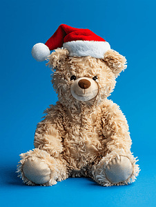 蓝色背景中戴着圣诞老人帽子的毛绒泰迪熊