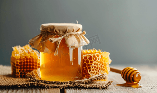 六边形网格底纹摄影照片_蜂蜜罐子里装着蜂巢和木勺