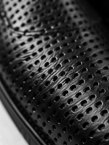 部分鞋子由黑色穿孔皮革制成特写