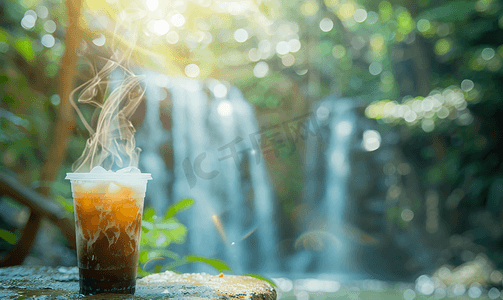 塑料杯中的冰咖啡和瀑布模糊背景的杆子上的蒸汽