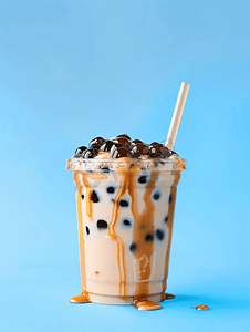 夏季果汁系列摄影照片_蓝色背景玻璃中的泡沫波巴茶加牛奶和木薯珍珠