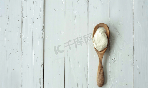 白色木质背景上木勺上的白色酸奶