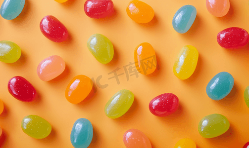 糖果豆摄影照片_橙色纸背景上的多色釉面果冻豆糖果