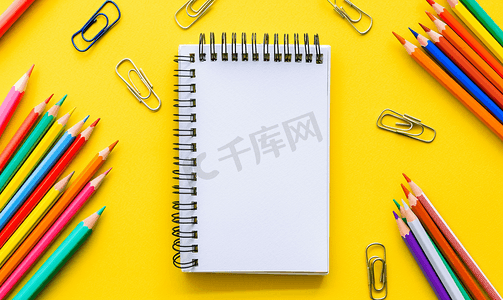 彩色铅笔创意艺术摄影照片_黄色背景上的水彩画彩色铅笔纸夹和记事本