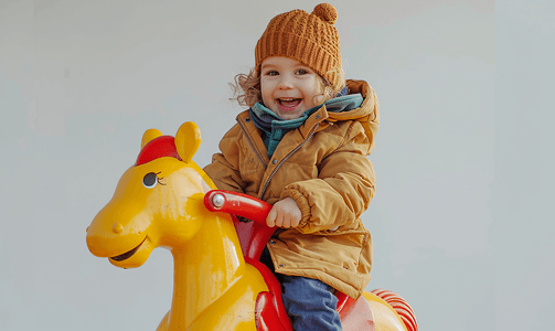 男孩骑摄影照片_一个快乐的孩子骑着摇马的照片
