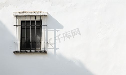 外墙logo摄影照片_房子的白墙上有一扇关闭的小窗户上面挂着黑色金属条