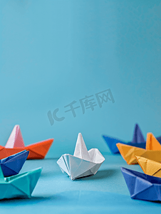 三折页蓝色模板摄影照片_蓝色背景中的白色纸船领先其他彩色纸船