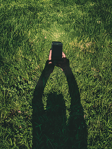 草地上用手机的人的影子