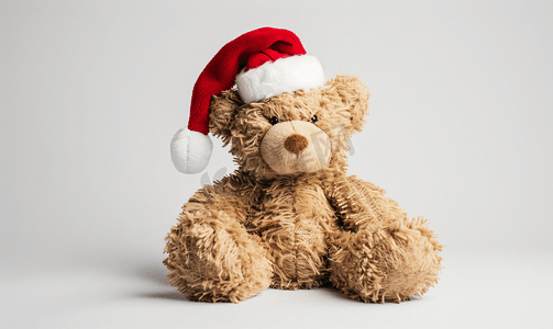 帽子冬天摄影照片_白色背景中戴着圣诞老人帽子的毛绒泰迪熊