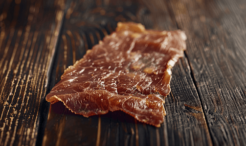 美味肉干摄影照片_肉片一块干肉位于深色木质表面上