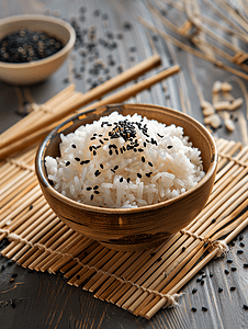 米饭筷子摄影照片_用筷子将米饭和黑芝麻放在竹席上蒸熟