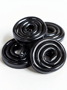 黑色螺旋背景摄影照片_白色上的一些盘绕的黑色甘草糖