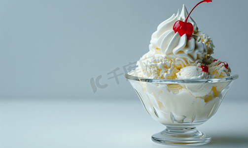 球冰淇淋摄影照片_玻璃碗里的冰淇淋上面有生奶油和红樱桃