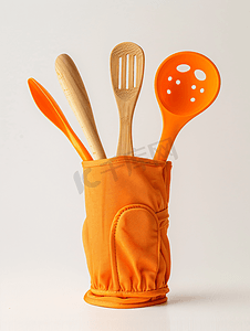 带手套摄影照片_白色背景中带厨房用具的橙色耐热烹饪手套