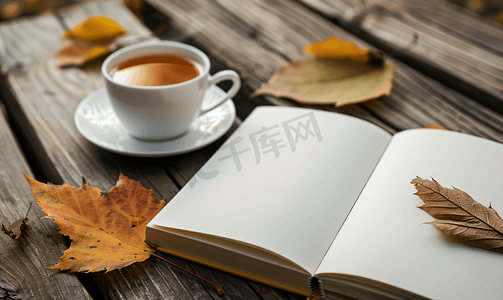 红色茶摄影照片_旧桌子上放着秋叶和一杯热茶的白色空白书模型设计