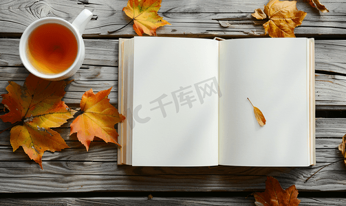 绘本阅读海报摄影照片_旧桌子上放着秋叶和一杯热茶的白色空白书模型设计