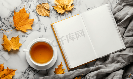 给心情放个假吧摄影照片_桌上有秋叶和一杯热茶的白色空白书本样机设计