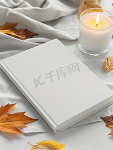 读后感背景图摄影照片_白色空白书白桌上放着秋叶、玻璃和蜡烛模型设计