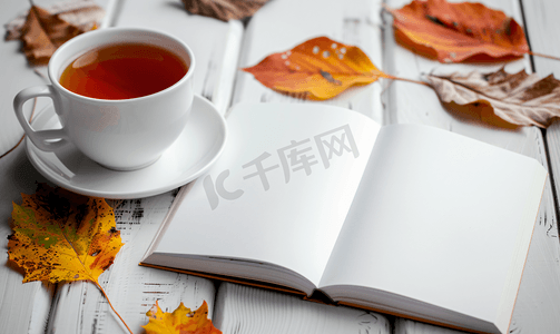 果茶店样机摄影照片_桌上有秋叶和一杯热茶的白色空白书本样机设计