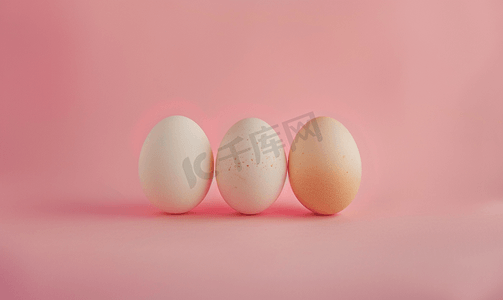 这是一张粉红色背景上三个挨着的鸡蛋的照片