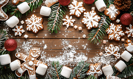 甜蜜活动摄影照片_圣诞木制背景配有树枝姜饼和棉花糖