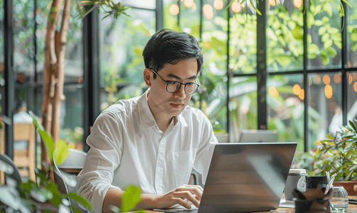 年轻亚洲经济学家在咖啡店使用笔记本电脑