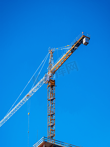 蓝天背景城市摄影照片_明亮的蓝天背景下带有起重机的在建建筑