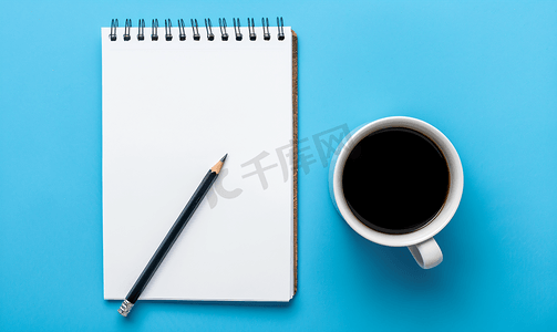 顶视图蓝色背景上有自动铅笔和黑咖啡的空白页规划器