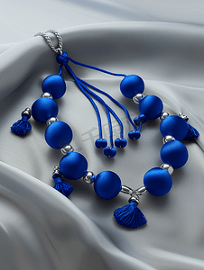 丝绸珠宝摄影照片_蓝色丝球和银戒指制成的项链