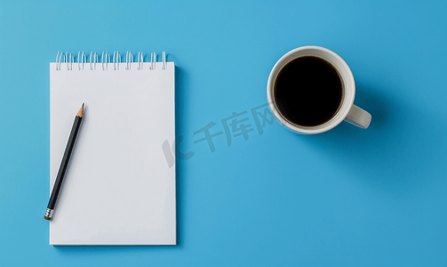 顶视图蓝色背景上有自动铅笔和黑咖啡的空白页规划器