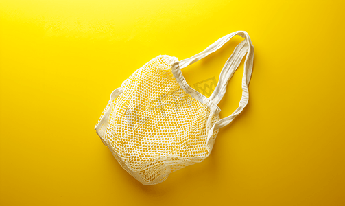 蔬菜超市摄影照片_黄色背景上有一个白色网状空袋