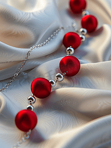 丝绸红色摄影照片_红色丝球和银戒指制成的项链