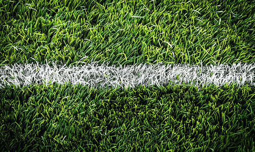 斜条纹底纹摄影照片_鲜绿色的人造草坪足球场上的白色条纹