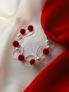 丝绸珠宝摄影照片_红色丝球和银戒指制成的项链