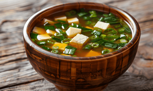日式味噌汤配葱和豆腐块放在棕色碗里的木桌上