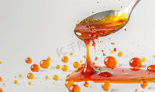 糖浆液体摄影照片_白色背景上的自制酱汁和勺子的滴