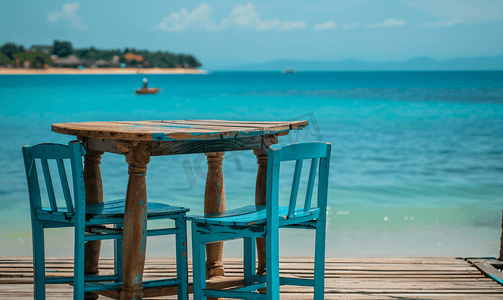 背景大海摄影照片_带海滩背景的木桌凳和椅子