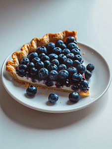 芝士蛋糕蛋糕摄影照片_白盘上的蓝莓芝士派